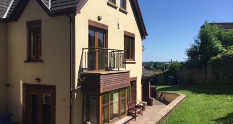 Outside of 2 storey yellow house showing patio doors to small balcony