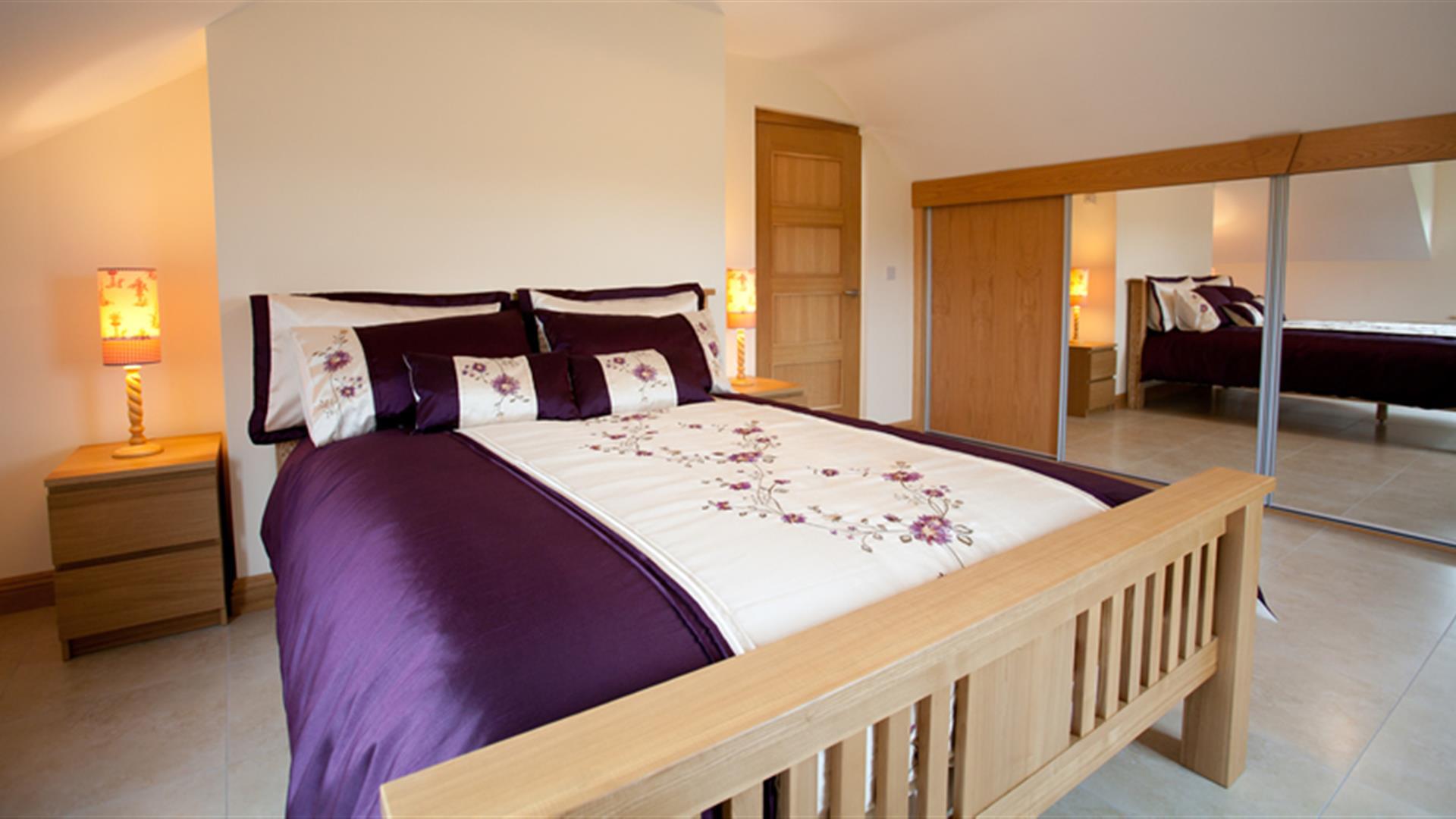 Double bedroom with sliding mirror wardrobe doors, double bed and bedside lockers