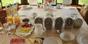 table set with breakfast options, including fruits, cheese, ham and cereals.