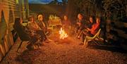 A group of people sitting chatting outside around a firepit