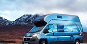 Image is of a campervan with view of snow covered mountains in the background