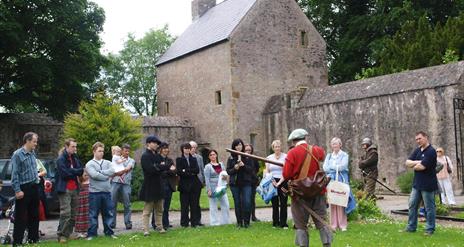 Group of people listening to a man in costume in front of Benburb castle