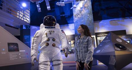 Girl smiles at life size model of astronaut suit