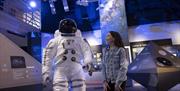 Girl smiles at life size model of astronaut suit