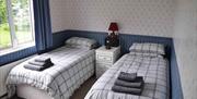 Two single beds with checked bedding and patterned wallpaper