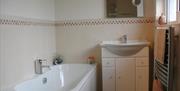 tiled bathroom with sink, bath and towel rack radiator in image