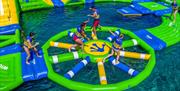 Children playing on a large inflatable assault course on water