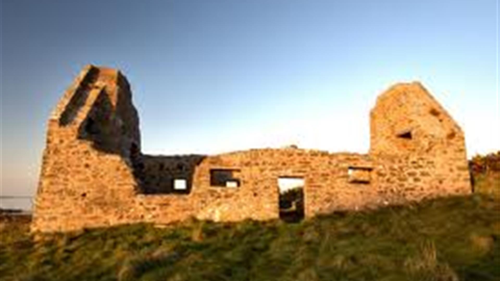 Image of the ruins at sunset with the light of the sun shining onto the remnants of the building