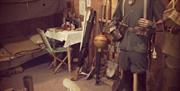 Image of staged bunker set showcasing life in war, featuring uniforms, sleep set up and dining set up as well as everyday items used to survive the wa