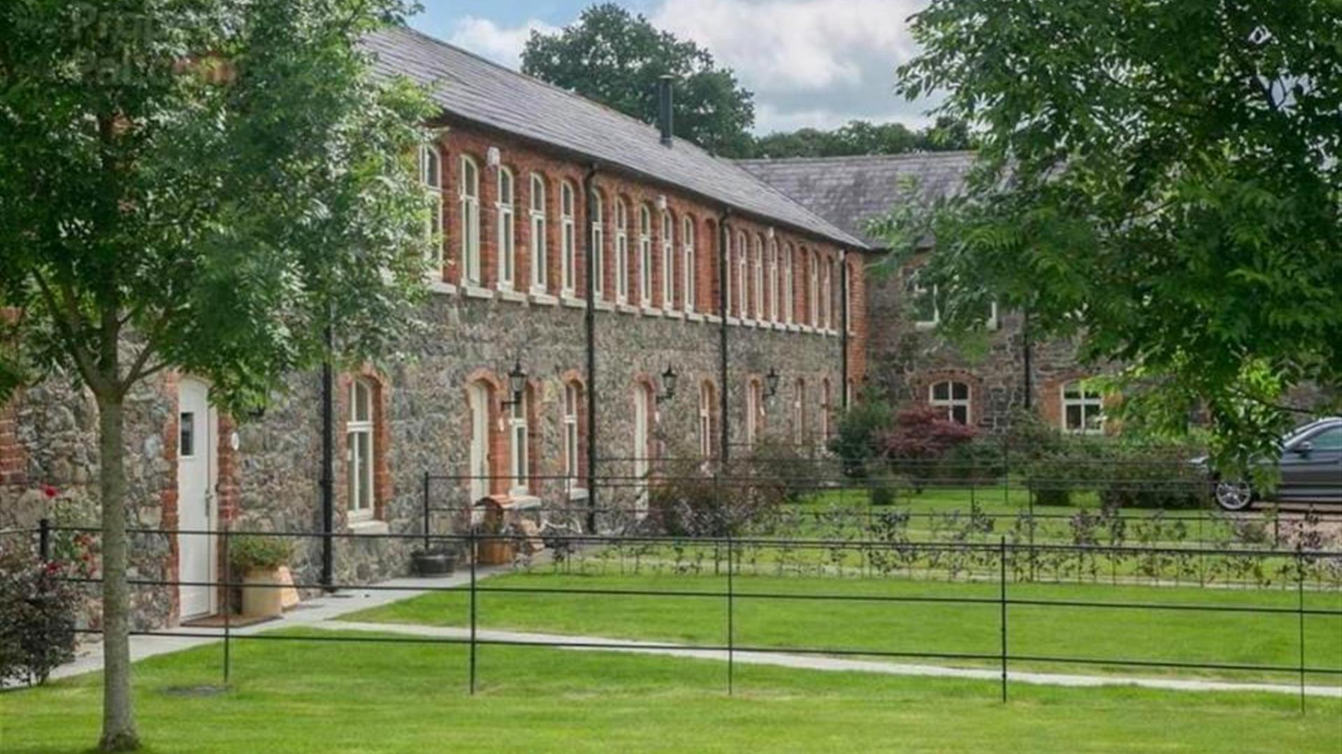 Image shows side view of property with lawn and trees in front