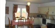 Image shows kitchen area with dining table and 6 chairs. Patio doors onto garden