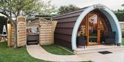 Glamping pod with hot tub beside enclosed with open gate
