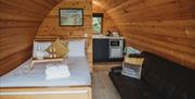 Inside glamping pod with single bed and black sofa.  Small kitchenette to back of the glamping pod