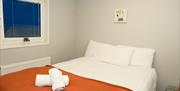 Double bed with white and orange linen