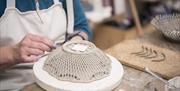 pottery maker at work bench making basket