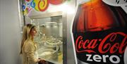 Image shows a woman watching coca cola making process through a viewing window
