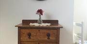 A chest of drawers with vase and flowers on top