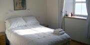 Double bed with white lined and towels folded on top