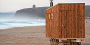 Mobile sauna sits on Benone Strand with Mussenden Temple in the background