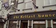 A black sign with the Belfast house written in golden letters