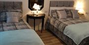 tripe room with 1 double bed and 1 single bed and table with lamp between