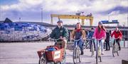 Steven from Hometown Tours leads a group of bicycling tourists along the Maritime Mile cycle path on Belfast's waterfront area.