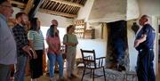A group of visitors listening to the tour guide inside Andrew Jackson Cottage standing by the fire.