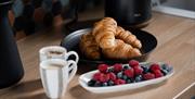 2 cups of coffee and plate of croissants and berries on table