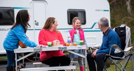 Family at table outside caravan