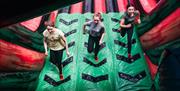 3 girls running up an incline at beat the wall in Inflata Park