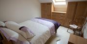 bedroom with double bed, wardrobes, chest of drawers and a chair