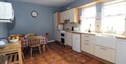 Image shows kitchen area with tiled floor and dining table with chairs