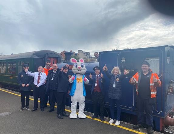 Group of volunteers with Easter Bunny standing outside steam train at Whitehead Railway Museum
