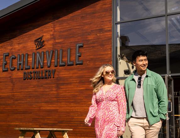 Couple walks outside the Echlinville Distillery in the sunshine