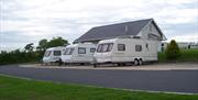 Image is of 3 motorhomes parked outside a small building