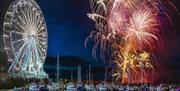 Fireworks burst to life above the boats in the marina with the big wheel lit up at the side