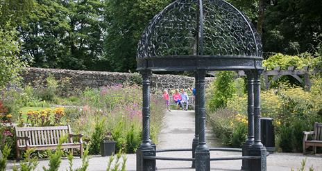 A couple and young child pictured through the arbour in Maghera Walled Garden.