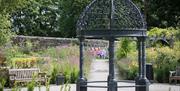 A couple and young child pictured through the arbour in Maghera Walled Garden.