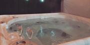Image is of large hot tub with 2 champagne glasses on a tray on the side
