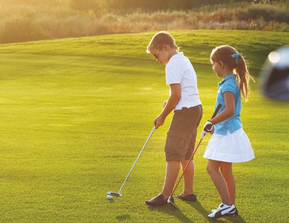 A young boy and a girl playing golf.