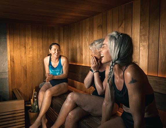 Three ladies laughing inside a sauna