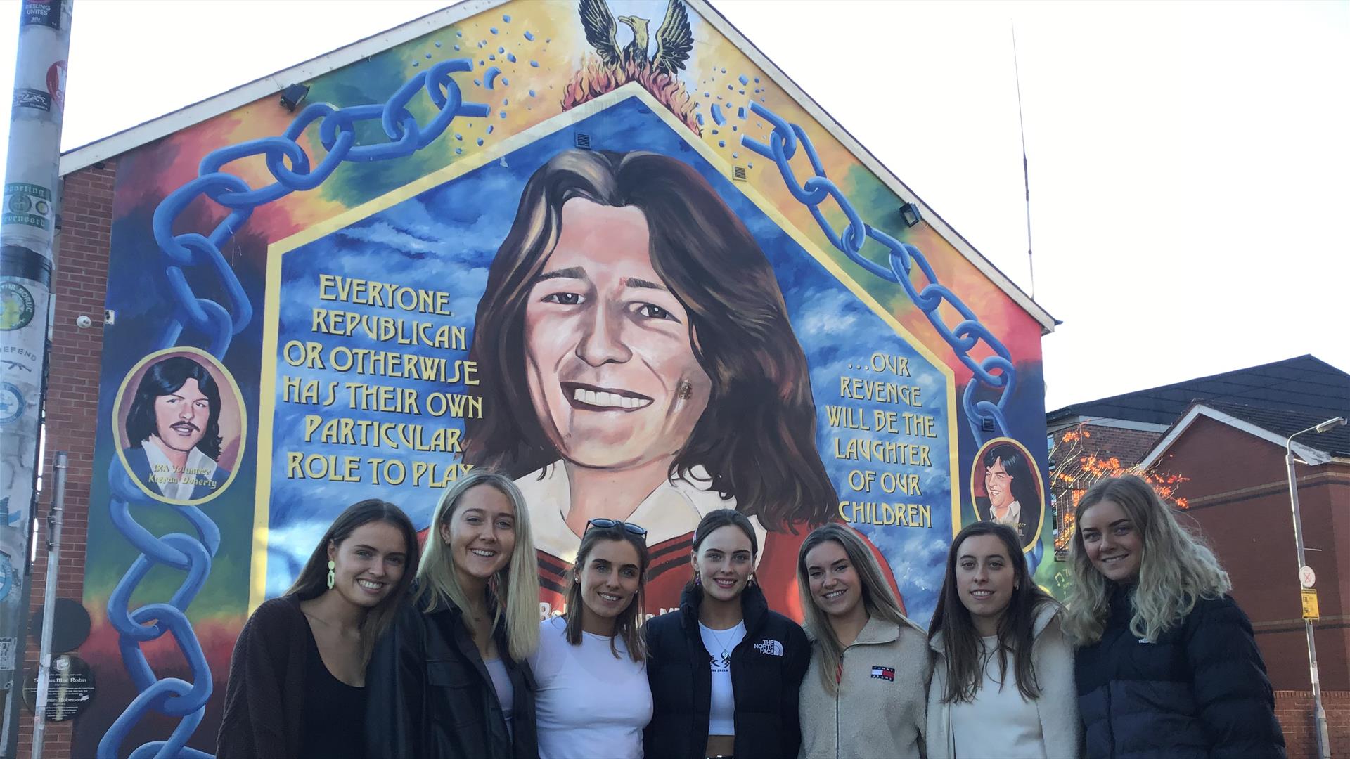 Bobby Sands mural Falls Road Belfast-  Group of visitors standing in front of mural.