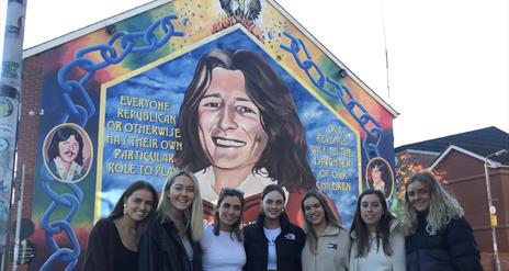 Bobby Sands mural Falls Road Belfast-  Group of visitors standing in front of mural.