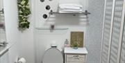White bathroom suite sink on the left with shel and mirror. Black and white flooring deep burgundy bathroom mat set.  Folding shower screen with elect