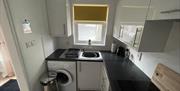 itchen to the left is the washing machine and window with yellow blind.  Kettle.  White units/ oven & hob in the other corner is the microwave and toa