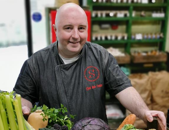 Chef Rob Curley holding a wooden box full of vegetables from Slemish Market Garden.