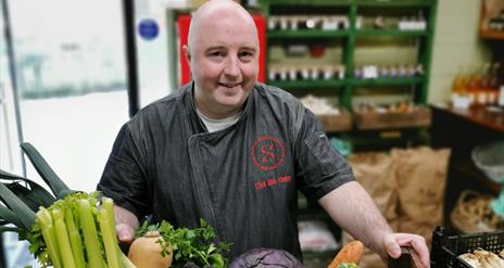 Chef Rob Curley holding a wooden box full of vegetables from Slemish Market Garden.