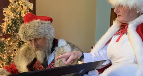 Santa and Mrs Claus reading the naughty and nice lists in Santa's study.