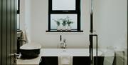 Monochrome bathroom featuring a free standing bath and rainwater shower.