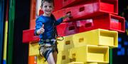 Little boy giving thumbs up while climbing in the Clip and Climb arena at High Rise Lisburn